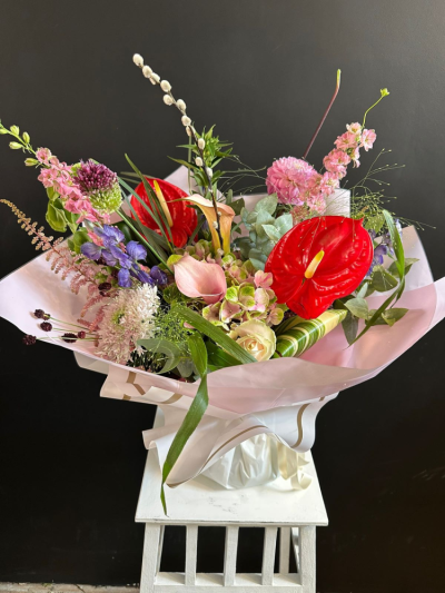 Crimson Charm - A striking hand-tied bouquet featuring vibrant seasonal flowers in bold red, soft pink and lilac tones, expertly arranged and gift wrapped by a local florist.